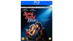 Song Sung Blue portrays Mike and Claire Sardina’s unlikely yet true musical dream, where love, struggle, and Neil Diamond tributes create a poignant and emotional cinematic experience.